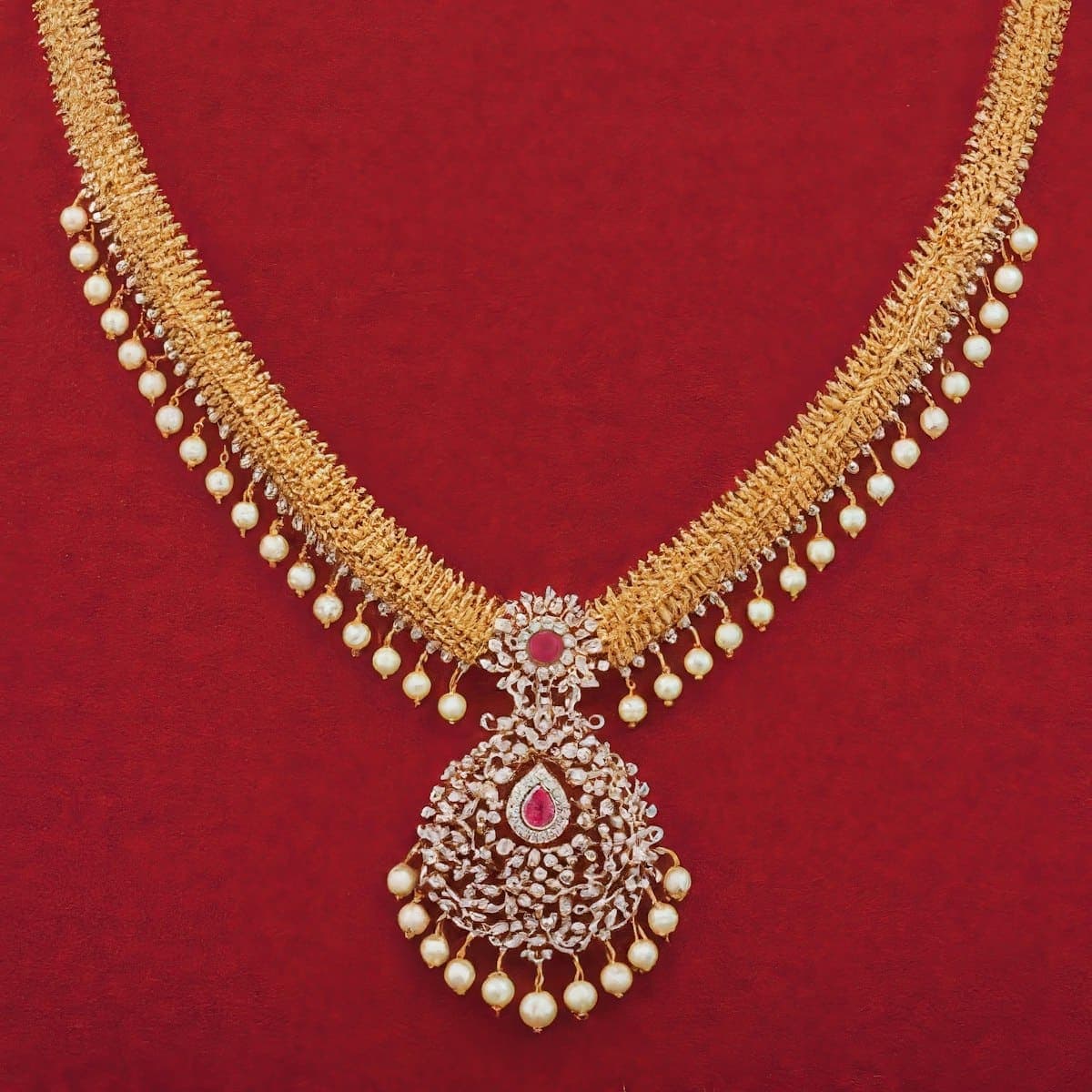 Gold-tone bridal necklace with pearl drops on red velvet
